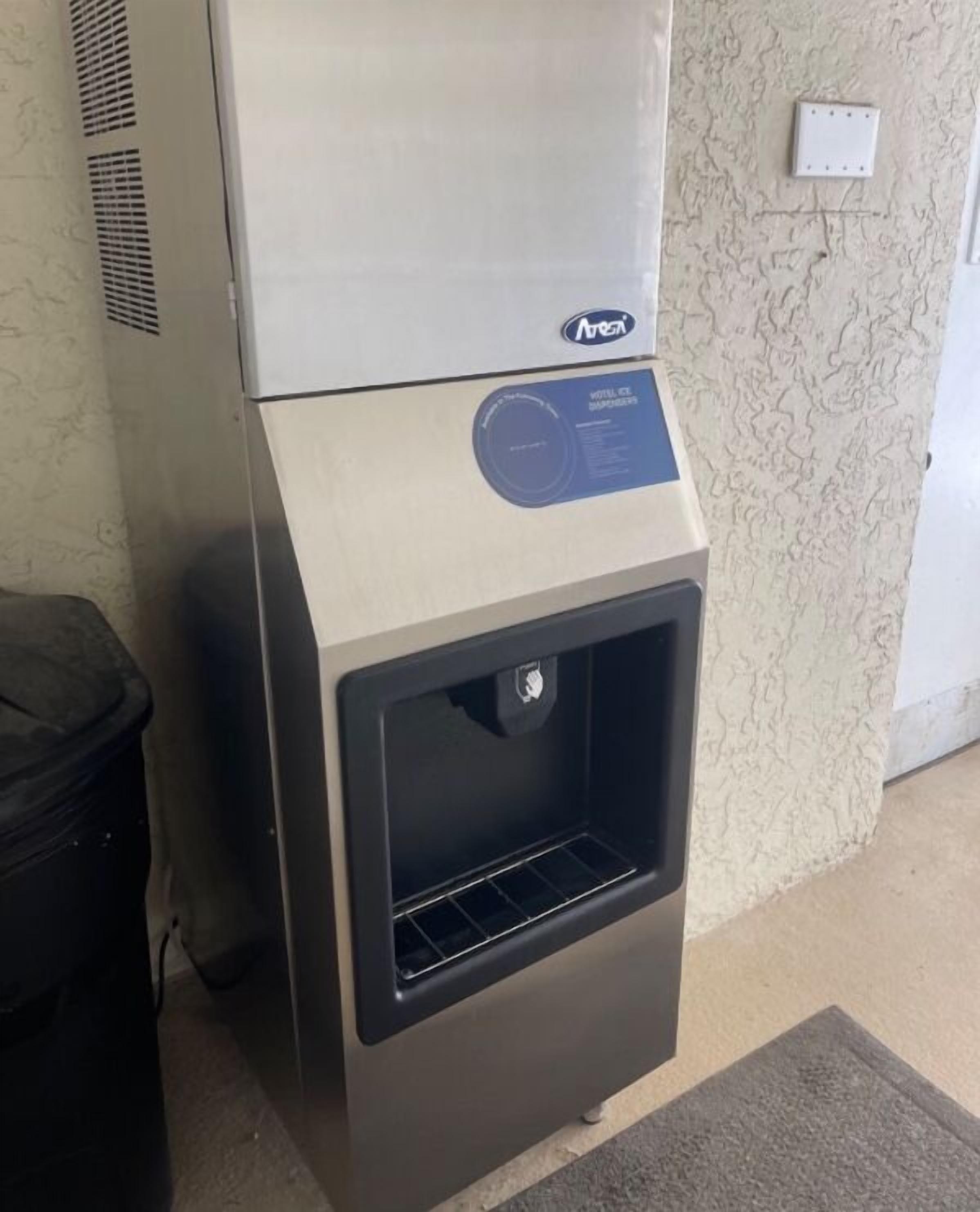 A compact, modern beverage dispenser with a control panel and a dispensing area, situated against a textured wall.