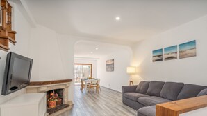 Una sala de estar moderna con chimenea, un sofá gris, una mesa de centro de madera y un comedor con mesa y sillas.