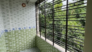 A room with patterned walls, a window with metal bars, and a ceiling light. - Saudia residential hotel (Sylhet)