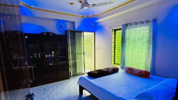 A bedroom with a bed, a wardrobe, a ceiling fan, and a window with curtains. - Saudia residential hotel (Sylhet)