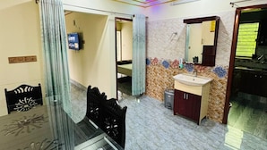 A dining area with a glass table and chairs, a ceiling fan, a TV, and a bathroom with a sink and mirror. - Saudia residential hotel (Sylhet)