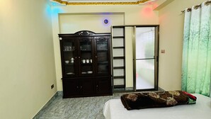 A bedroom with a bed, a wardrobe, a ceiling fan, and a door leading to another room. - Saudia residential hotel (Sylhet)