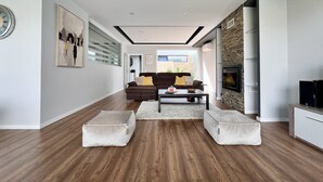 A modern living room with a sofa, ottomans, a coffee table, and a fireplace. - Casa Giumeni - House with swimming pool (Fernão Ferro)