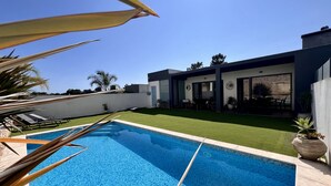 A modern pool area with a clear blue pool, a patio with lounge chairs, and a well-maintained lawn. - Casa Giumeni - House with swimming pool (Fernão Ferro)