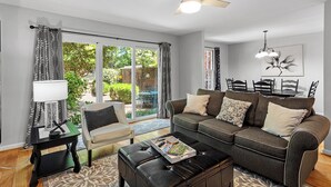 A modern living room with a sofa, coffee table, and a dining table with chairs. - Raleigh Retreat close to NCState, DWNTN and Rex (Raleigh)