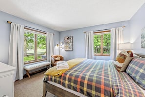 A bedroom with a bed, bench, and windows.