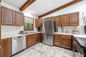 A modern kitchen with wooden cabinets, stainless steel appliances, and a dishwasher.