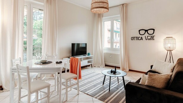 A modern living room with a dining area, a television, and a wall sign. - VALLI - MyHomeinComo (Como)