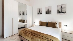A bedroom with a bed, a wardrobe, a mirror, and three cityscape posters on the wall. - VALLI - MyHomeinComo (Como)