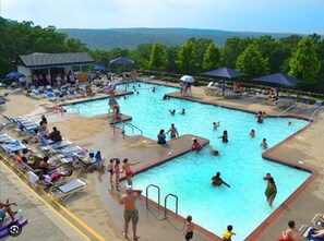 A pool area with multiple swimming pools, sun loungers, and umbrellas.