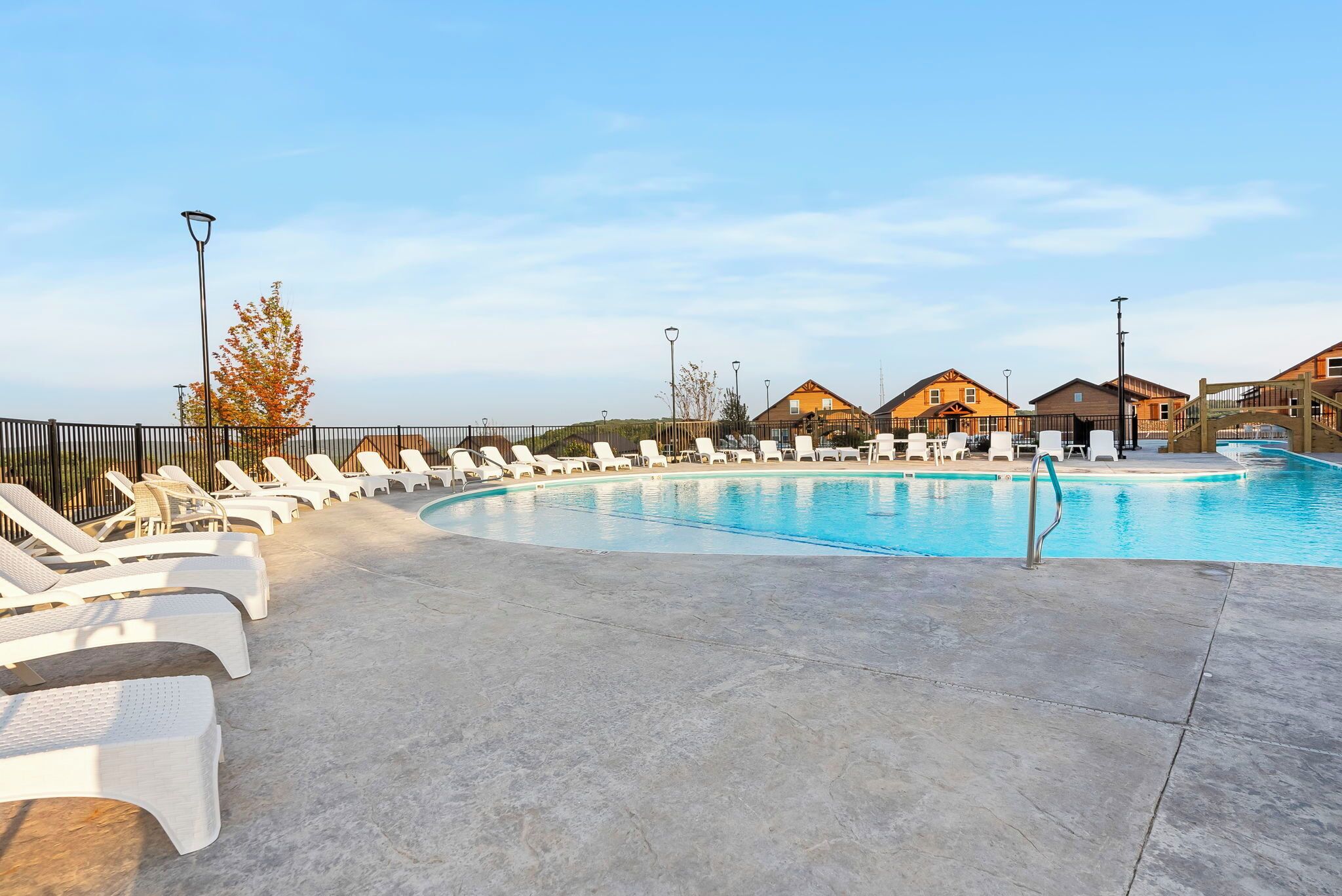 Une piscine entourée de maisons, avec des chaises longues et une terrasse en bois.