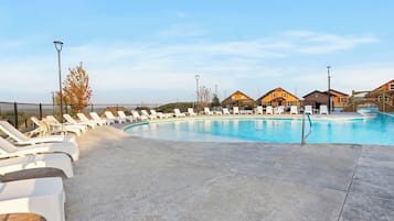 Une piscine entourée de maisons, avec des chaises longues et une terrasse en bois.