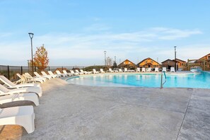 A swimming pool with lounge chairs and a wooden deck, surrounded by houses.