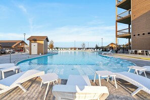 A pool area with lounge chairs and a small building, likely a changing room or utility room.