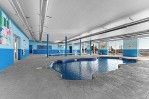 Une grande piscine intérieure aux murs bleus et au sol en béton.
