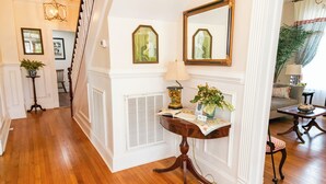 A wooden-floored hallway with a table, a chair, and a lamp.