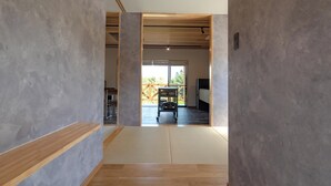 Un intérieur moderne avec un plancher en bois qui mène à une pièce dotée d’une grande fenêtre, d’un canapé noir et d’une table à manger.