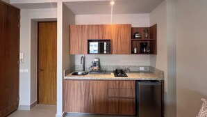 A compact kitchen with wooden cabinets, a built-in microwave, a coffee maker, and a dishwasher.