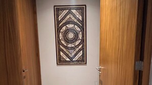 A hallway with wooden doors, a tiled floor, and a framed wall decoration.