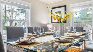A dining area with a glass table set for six, including plates, cutlery, and wine glasses.