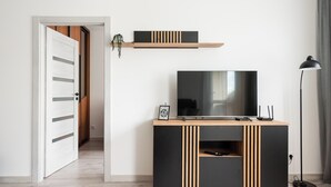 A modern living room with a flat-screen TV, a wooden coffee table, and a floor lamp.