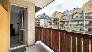 A balcony with a wooden railing overlooking a residential area with multi-story buildings.