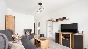 A modern living room with a grey sofa, wooden coffee table, and a TV on a wooden cabinet.