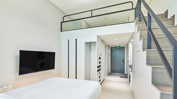 A modern hotel room with a bed, a TV, a wardrobe, and a staircase. - Travelodge Suites Busan Centum (Busan)