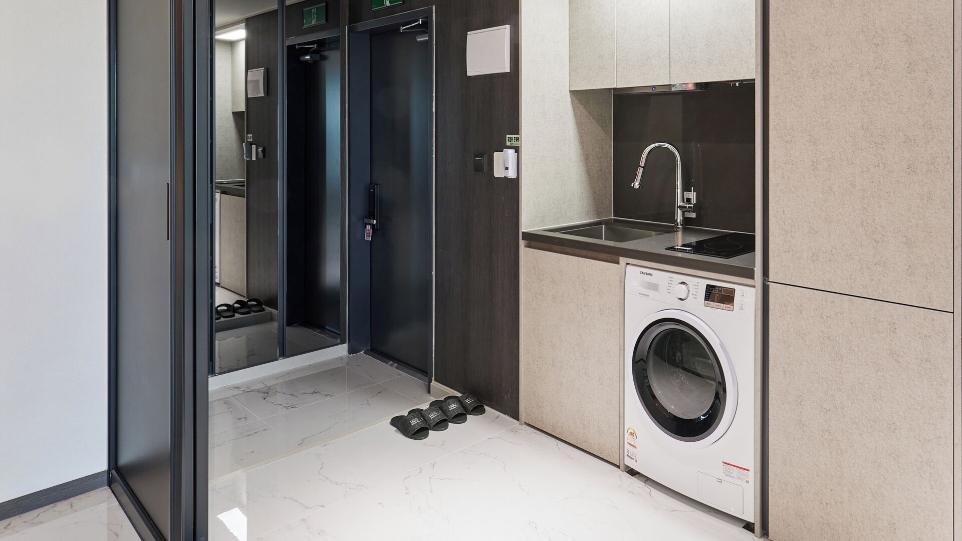 A compact bathroom with a washing machine, a sink, and a shower stall.