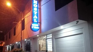 A hotel with a neon sign, a garage door, and a small tree in front. - HOTEL D MARTIN (Coishco)