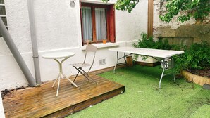 Ein kleiner Patio-Bereich mit einer Holzterrasse, einem weißen Tisch und einem Stuhl.