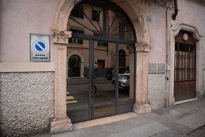 A building entrance with a no parking sign, a large arched doorway, and a street view.