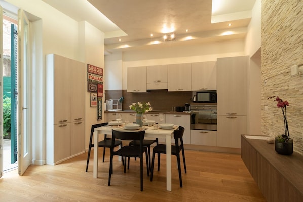 A modern kitchen with white cabinets, a dining table set for four, and a stone accent wall.