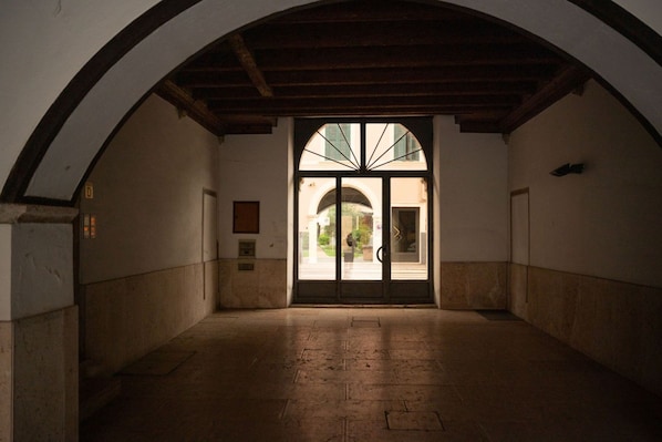 An arched hallway with a tiled floor leading to a door with a glass panel.