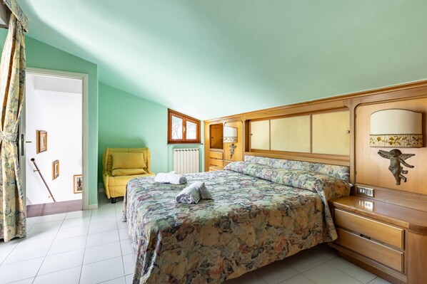 Un dormitorio con cama, cómoda de madera, silla y radiador.