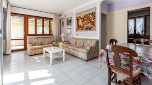 Een woonkamer met twee banken, een salontafel, een eettafel met stoelen en een schilderij aan de muur.