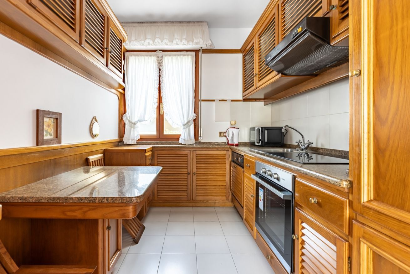 Cocina compacta con muebles de madera, horno integrado y encimera.