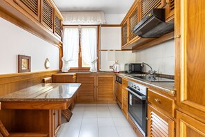 Cocina compacta con muebles de madera, horno integrado y encimera.
