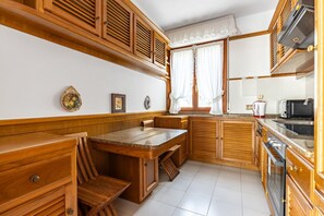 A kitchen with wooden cabinets, a granite countertop, a sink, a stove, and a window with curtains. - GuestHost - Spacious apartment of approximately 140 sqm, able to accommodate up to 4 people, located on the second floor of a building with lift (steps to access it).The property is located in a quiet area in the heart of Viareggio centre, a few minutes  (Viareggio)