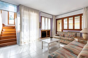 Una sala de estar con sofá, mesa de centro, chimenea y una escalera.