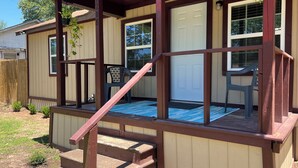Una terraza de madera con un tapete azul, una puerta blanca y una silla.