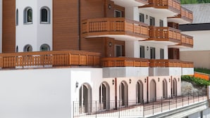 A multi-story hotel with wooden balconies and arched windows, set against a mountainous backdrop. - Apartment B01 by Interhome (Leukerbad)