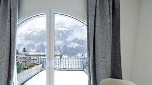 A room with a large window overlooking a snowy mountain landscape. - Apartment B01 by Interhome (Leukerbad)