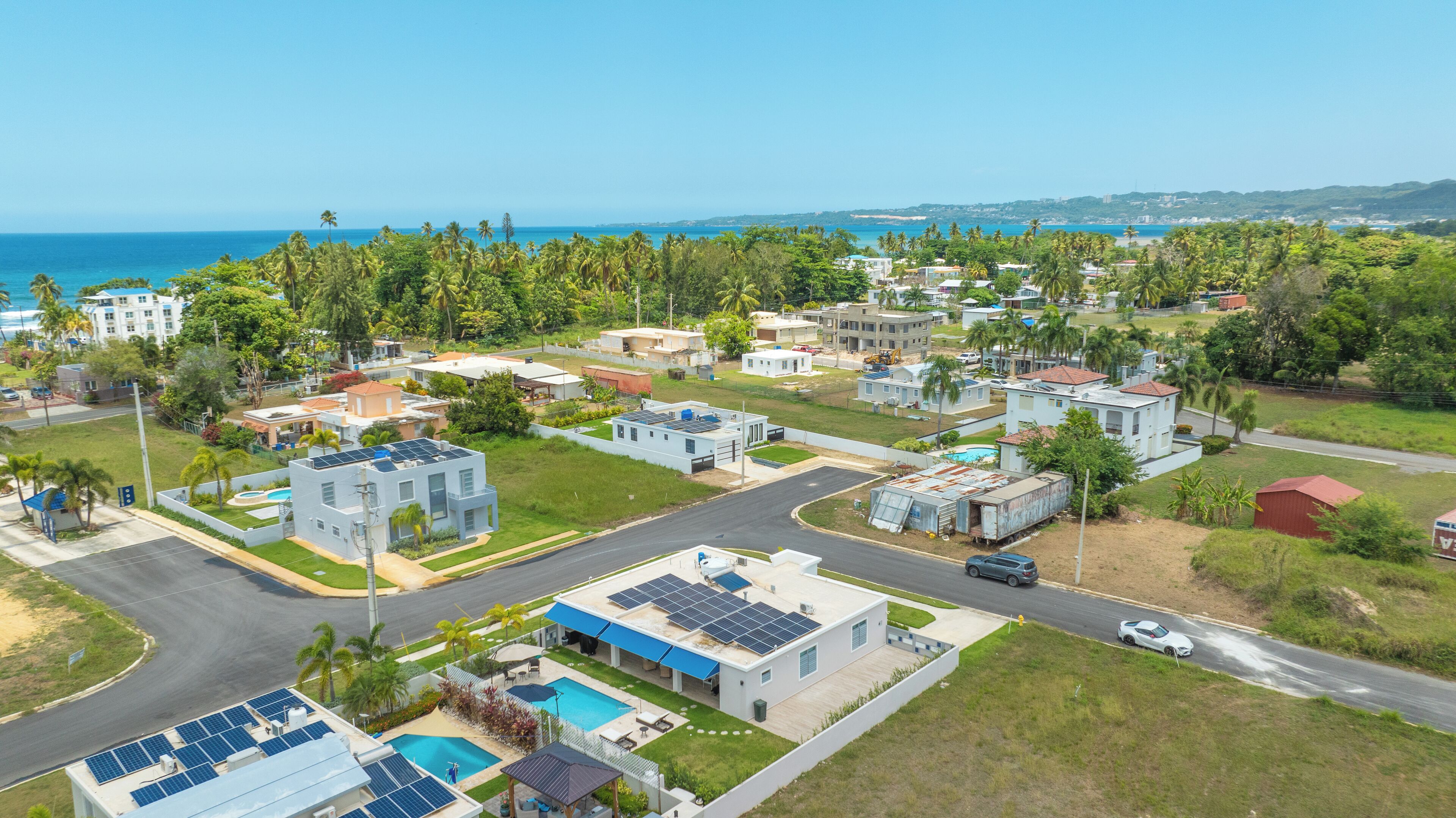 A residential area with modern houses, a swimming pool, and a view of the ocean.
