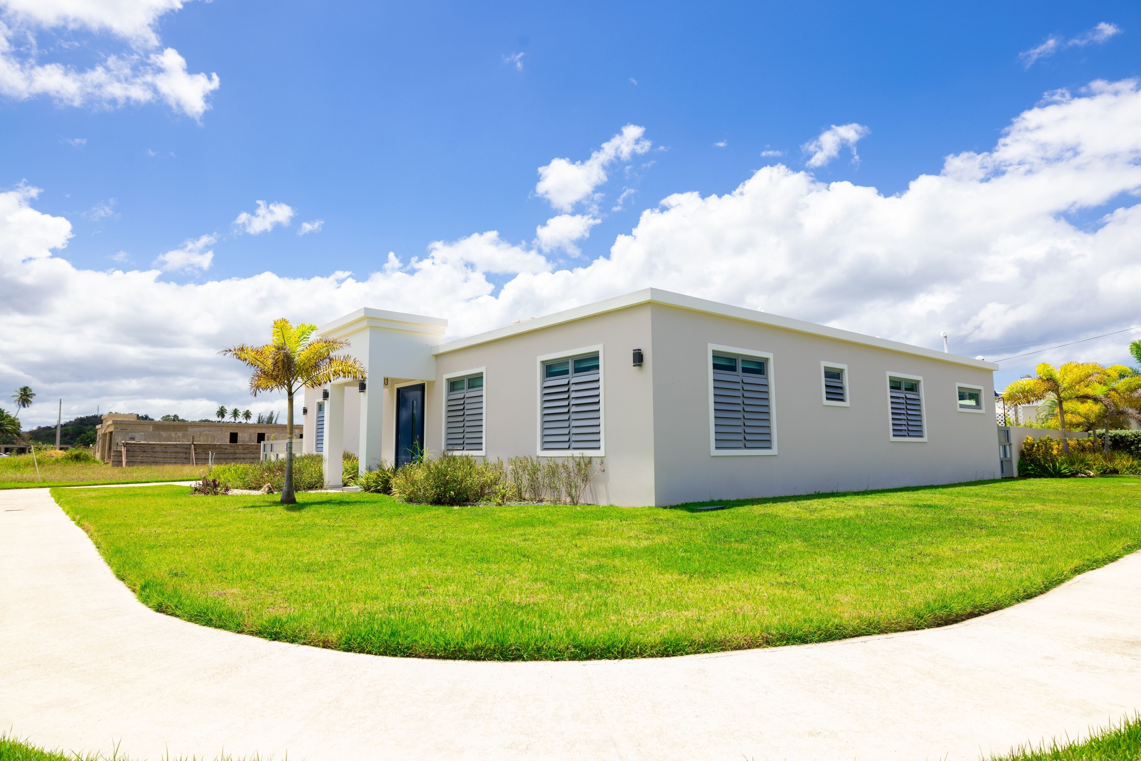 A modern two-story house with a flat roof, large windows, and a well-maintained lawn.