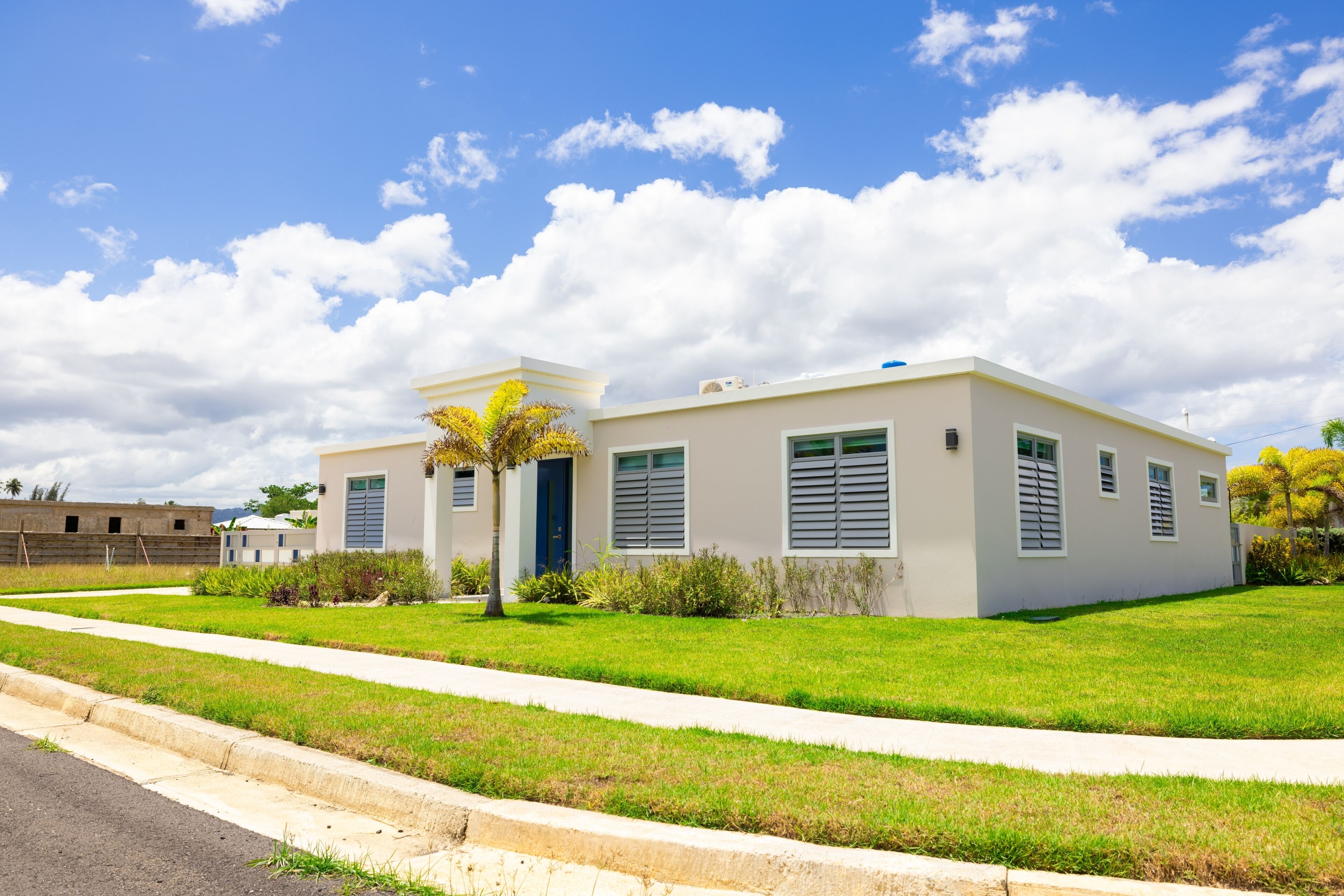 A modern two-story building with a flat roof, large windows, and a well-maintained lawn.