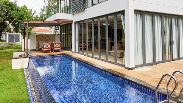 Ett modernt hus med en swimmingpool, stora fönster och en uteplats.