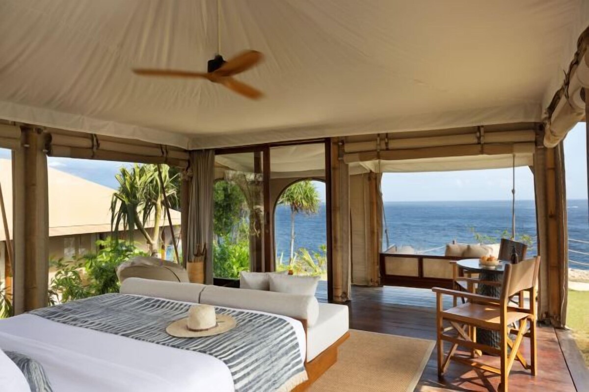Una habitación con carpa, una zona de comedor y vista al océano.