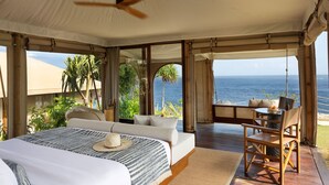 Un dormitorio amplio con una cama grande, una zona de comedor y vista al océano.