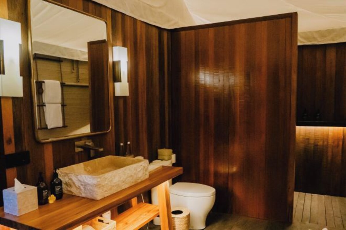 A bathroom with a wooden vanity, a large mirror, and a white toilet.